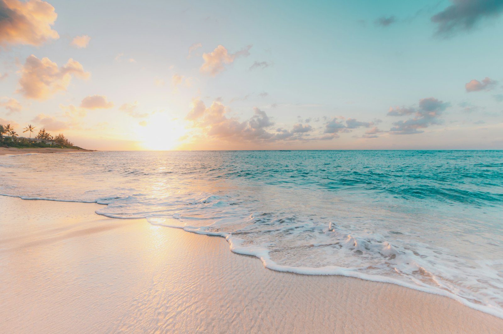 Gentle waves washing over golden sand at sunset on an Oʻahu shore